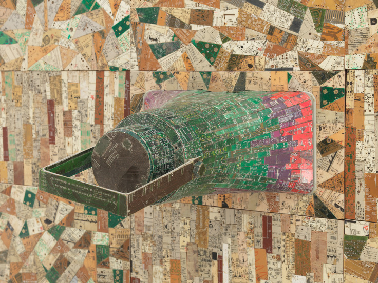 close up of a megaphone covered in electrical components emerging from a surface also composed of electrical components