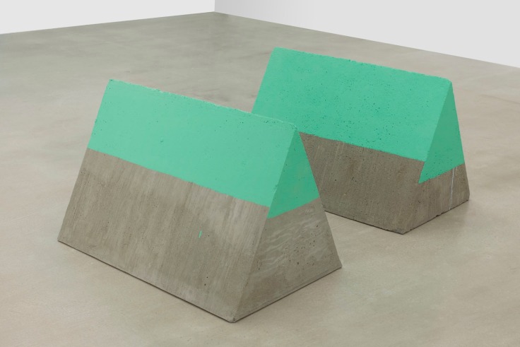 two triangular-shaped slabs of concrete with their upermost part painted in a greenish tone