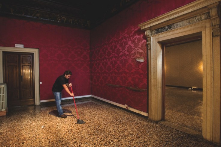 Man mops floor in a room with crimson wallpaper