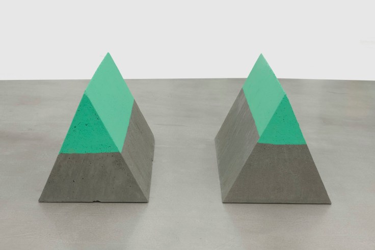 two triangular-shaped slabs of concrete with their upermost part painted in a greenish tone