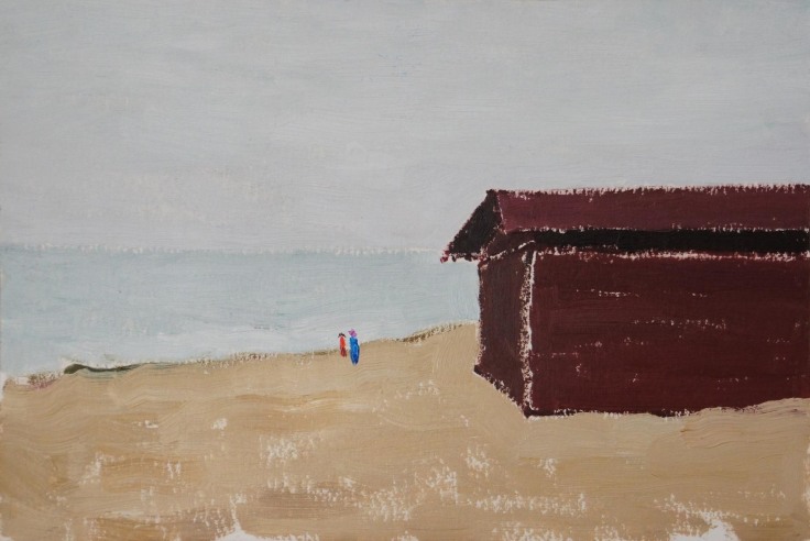red building by the beach with two very small figures nearing the shore