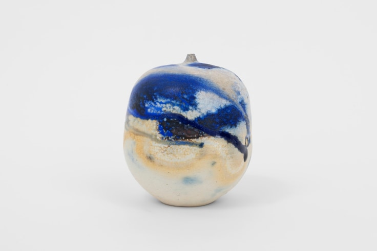 small closed ceramic form covered in white and blue glaze