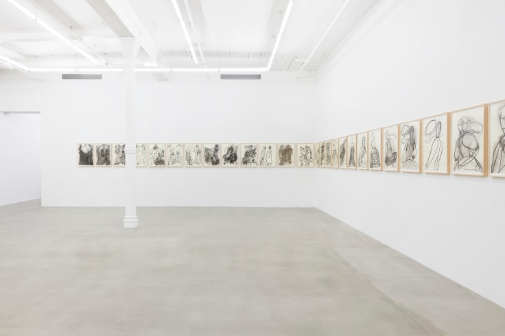 collection of drawings lined up in a row spanning two walls