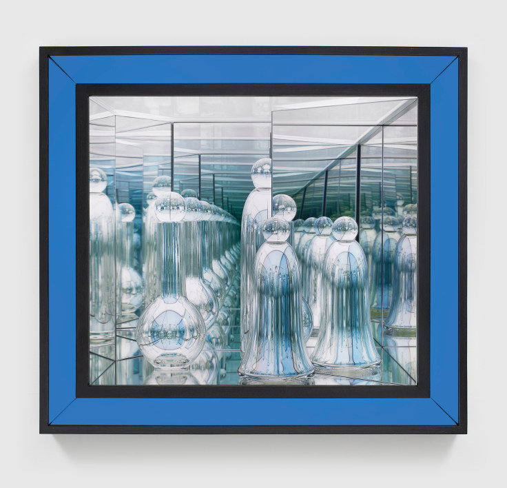 Handblown glass sculptures with reflective surfaces in a lit infinite space framed behind a blue dyed walnut frame