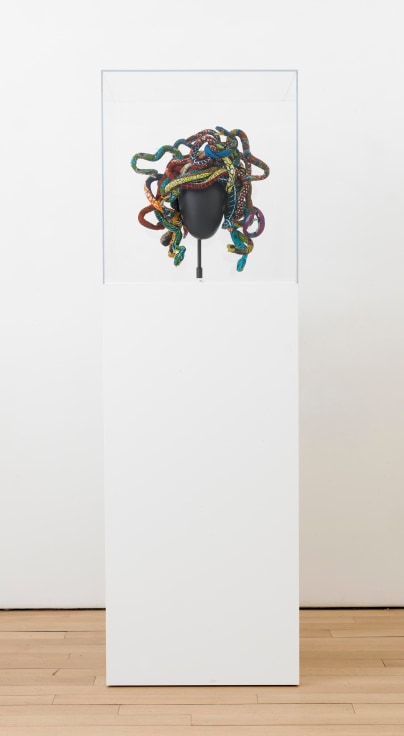 Medusa headpiece made up of many colorful snakes held up on a pedestal