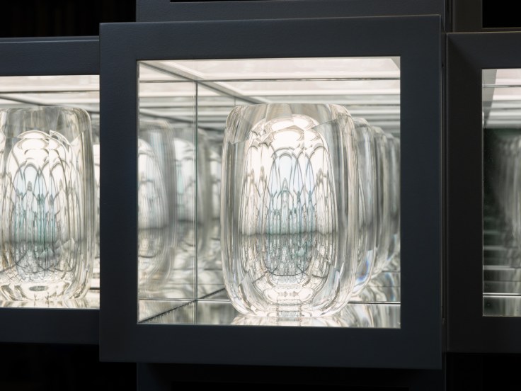 Close-up view of a lit in-laid box with reflective glass sculpture inside