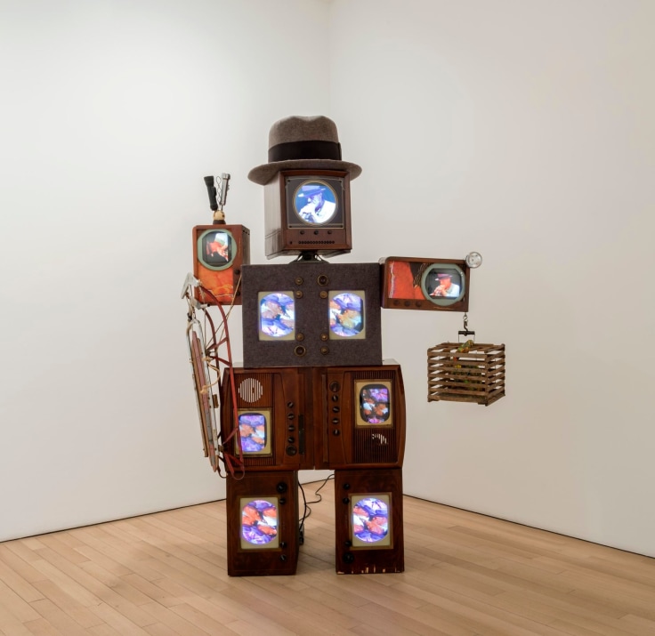 a man made out of televisions wearing a hat and holding a bird cage