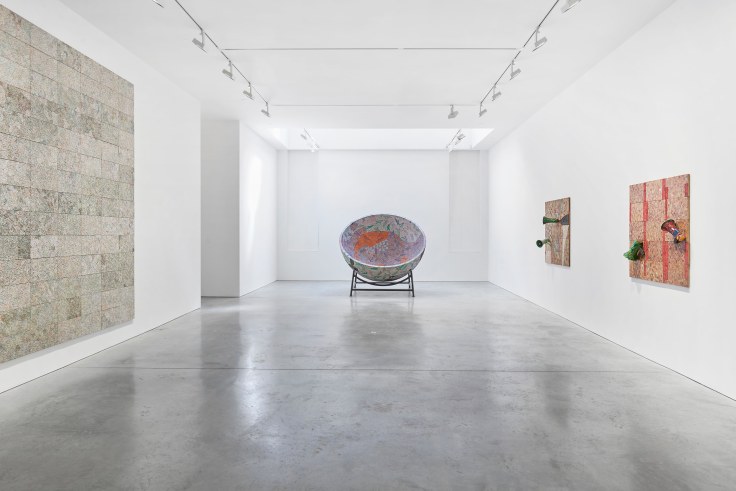 gallery view with three artworks and a large sculpture in the center
