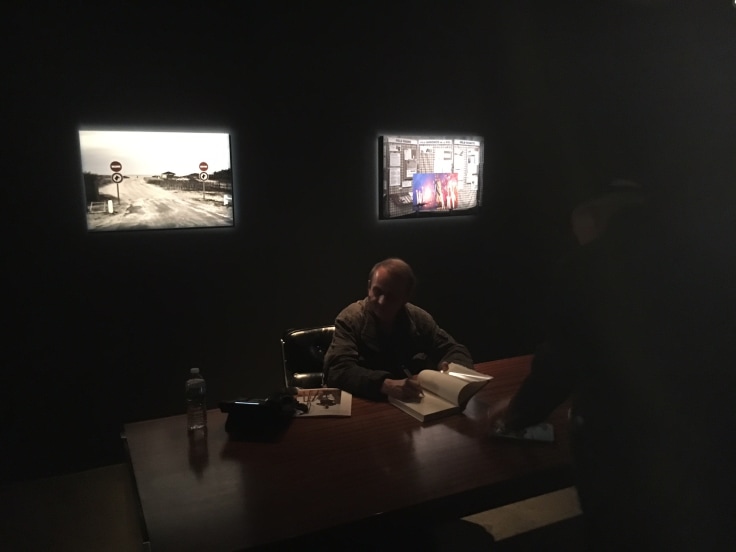 NOVELIST, POET, AND ARTIST MICHEL HOUELLEBECQ SIGNING COPIES IN THE DARK AT THE OPENING OF HIS SHOW &quot;MICHEL HOUELLEBECQ: FRENCH BASHING&quot; &nbsp;ON FRIDAY IN NEW YORK. PHOTO CREDIT: JOEL WHITNEY