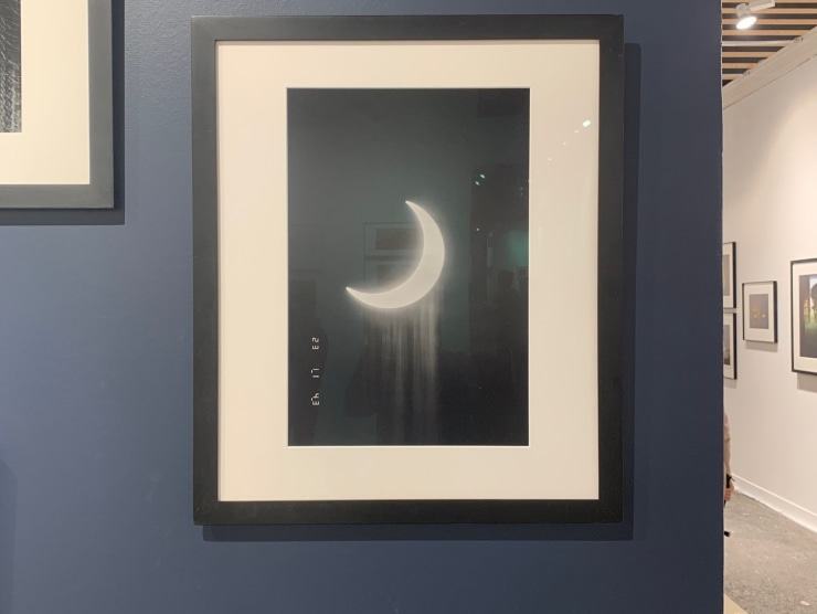 Installation view of a black and white framed photo of the crescent moon