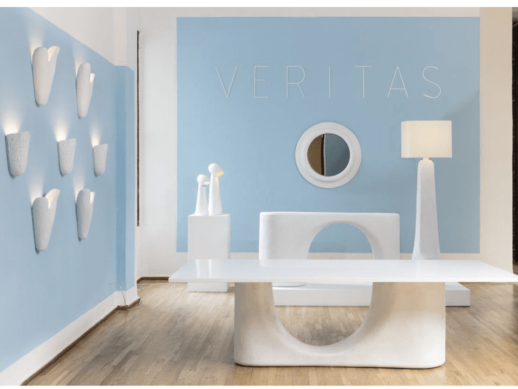 A modern interior with white sculptural surfaces, lamps, and sconces against two baby blue walls.