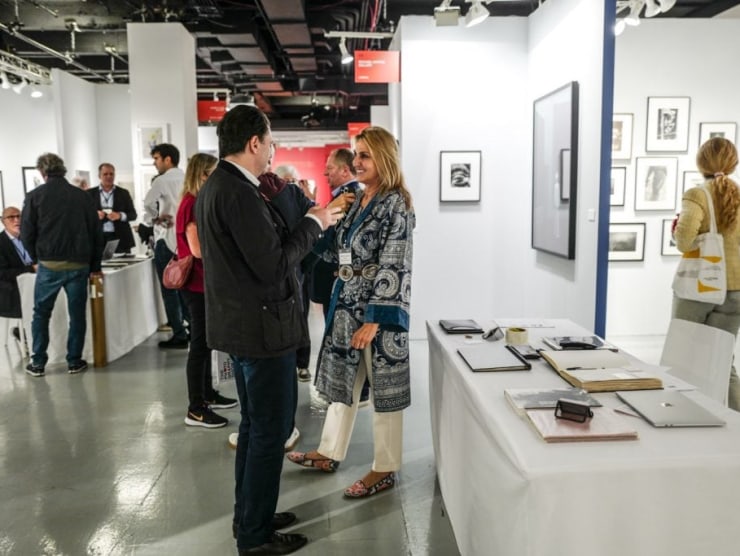 A woman smiles while talking to a man in the aisles of The Photography Show.