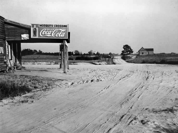 A black and white photograph of a desolate town with a Coca Cola ad