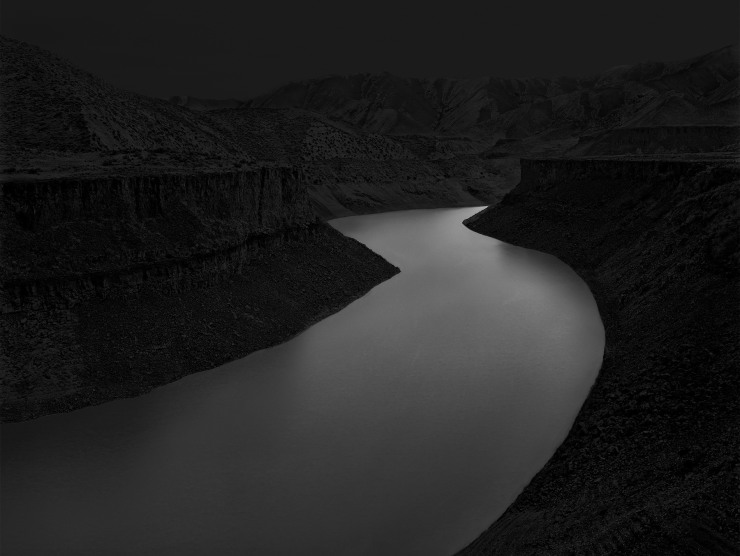 A river glows in a dark desert landscape