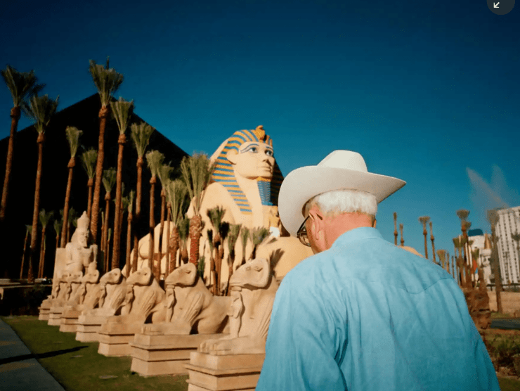 A man in a cowboy hat walks towards the Luxor Hotel pyramid and a painted smaller version of the Sphinx in Las Vegas.