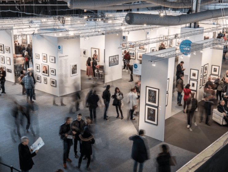 The Photography Show is shown from above while people mingle and look at art in booths