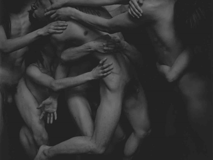 Several naked men and women move together and are intertwined