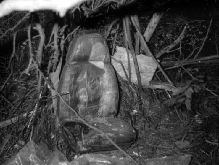 An abandoned car seat sits in a pile of detritus and is photographed in black and white