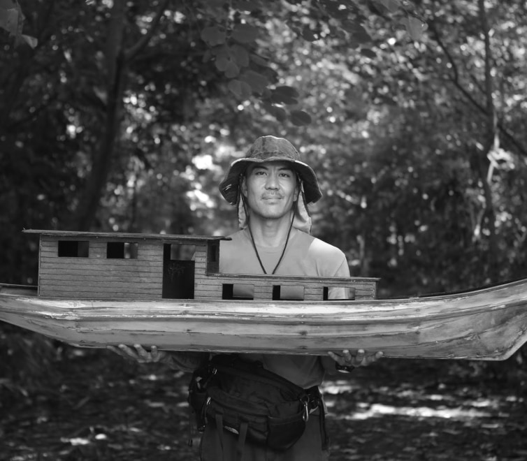 man holding a medium-sized wooden boat