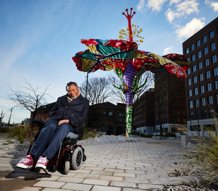 Image of Yinka Shonibare CBE and his sculpture Hibiscus Rising in Leeds, UK, 2023.