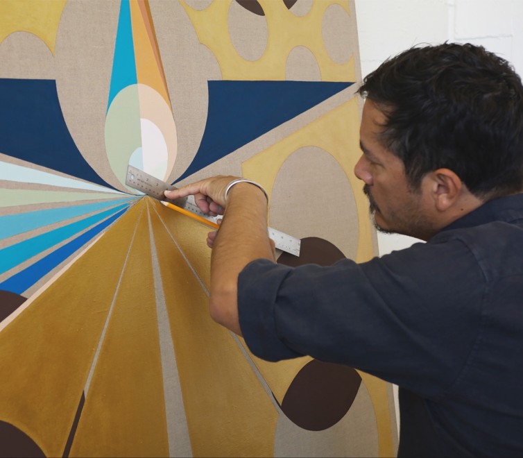 Eamon Ore-Giron using a ruler on one of his paintings