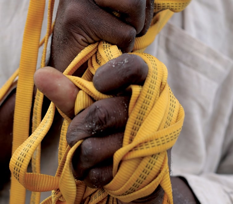 hands tangled in a yellow, narrow, woven fabric