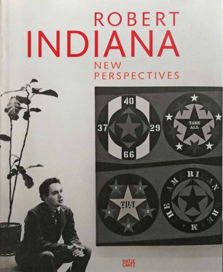 Cover of the book Robert Indiana: New Perspectives featuring a black and white image of Robert Indiana seated next to his painting The American Dream, I