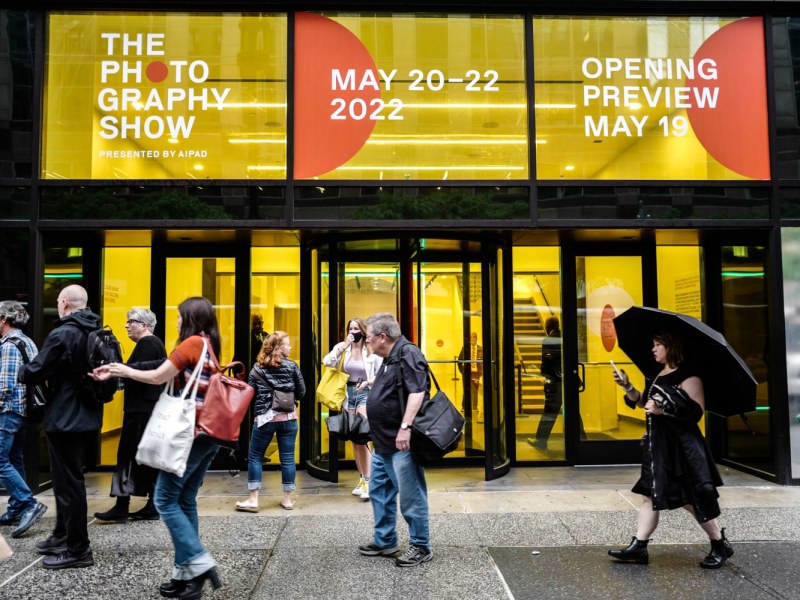The front of Center 415, the venue for 2022's iteration of The Photography Show, which has revolving doors with yellow clear film on the windows and orange and white signage.