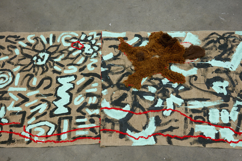 Alex Chaves, &quot;Amerikan Green Cross Rug,&quot;&nbsp;2015. Burlap, house paint, yarn, stuffed animals.