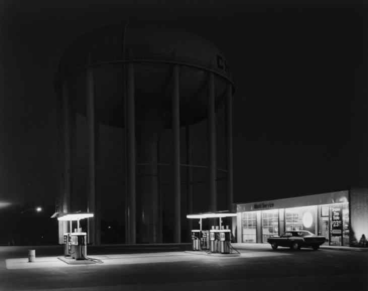 A gas station is photographed at night in black and white.