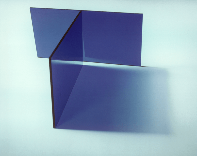 Two transparent vertical rectangles intersect causing a blue shadow on a light blue background.