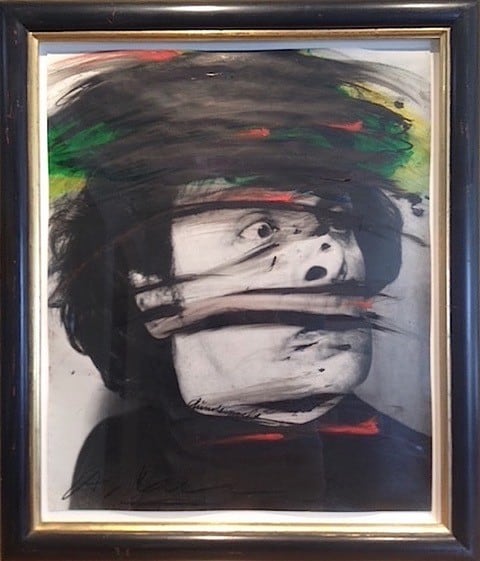 A black and white framed image of a man's surprised face with colorful paint added
