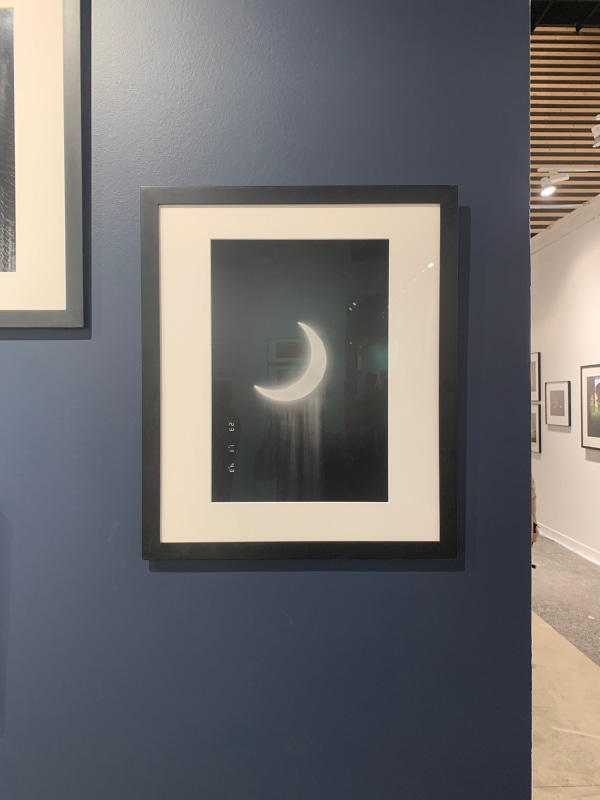 Installation view of a black and white framed photo of the crescent moon