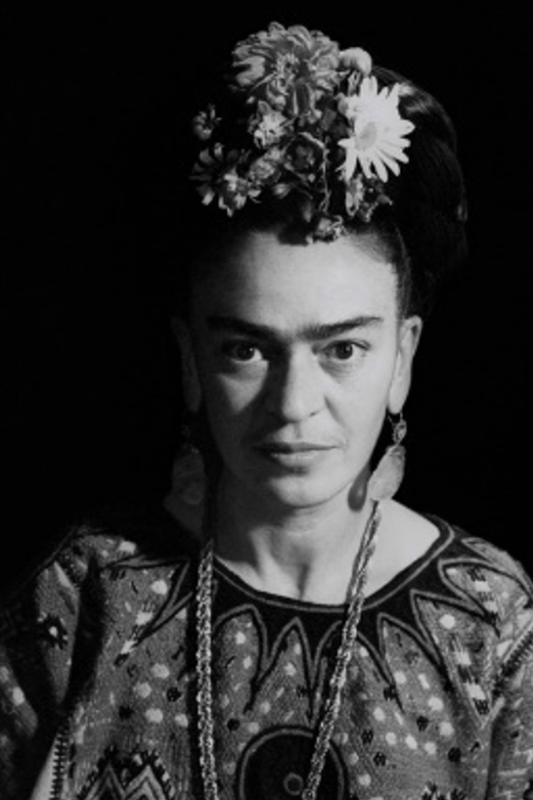 A black and white photo of the famous artist Frida Kahlo looking into the camera