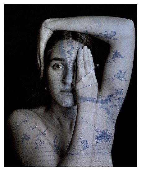 A woman takes a self portrait and has images of the zodiac superimposed on her body in blue.