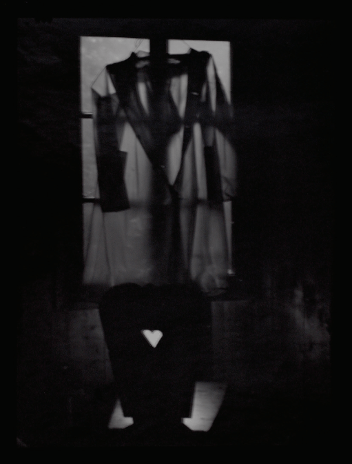 Black and white photo of a clear raincoat hanging against a window