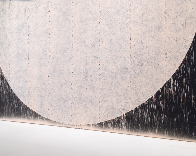 rectangular floor sculpture made up of pieces of flint rock with a vinyl wall text artwork in the background 