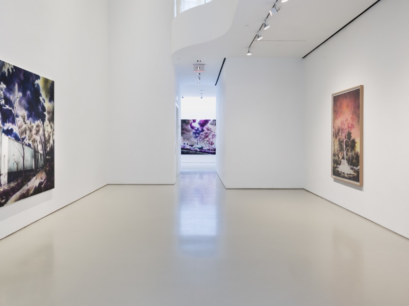 art gallery with one large painting on left wall and two framed works on paper on the right wall. Straight ahead in the back of the gallery hangs another large painting