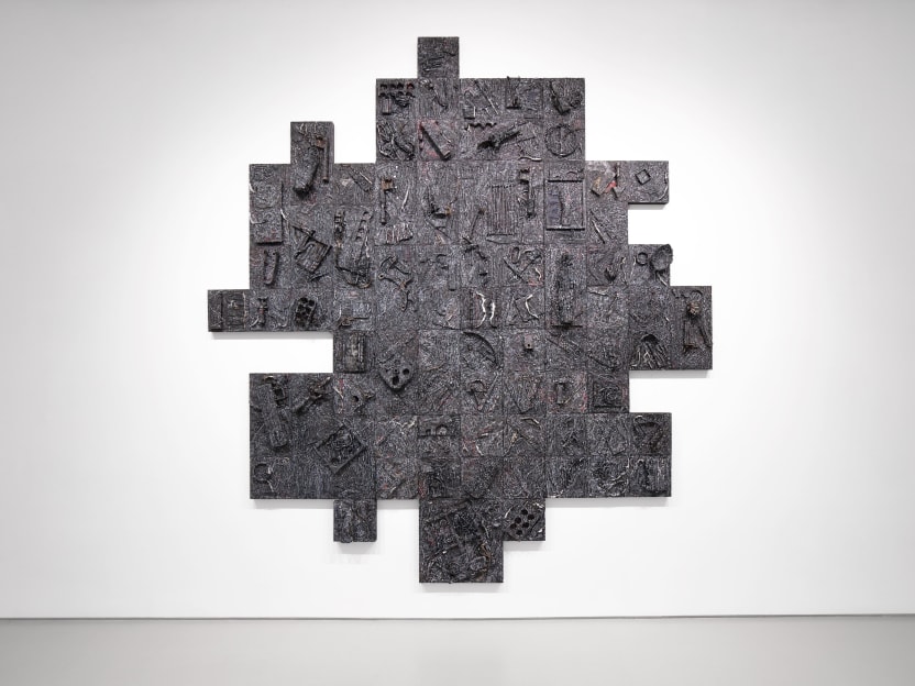 A black geometric artwork hangs on a white wall.
