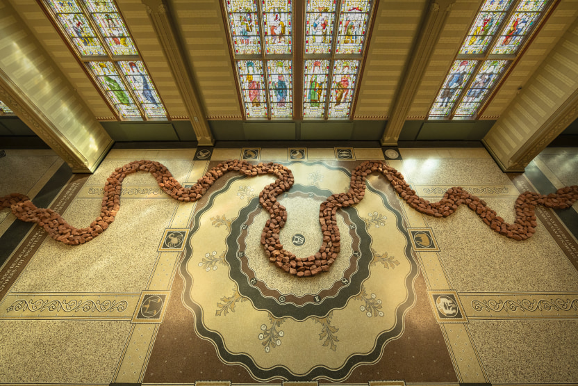 A path of red stones snake across an elaborate marble floors, illuminated by three stained-glass windows