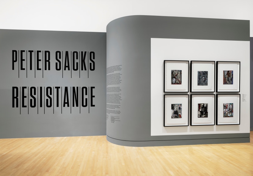 installation view of the entrance to Peter Sacks: Resistance with exhibition wall text and a grid of framed portraits hanging on the wall