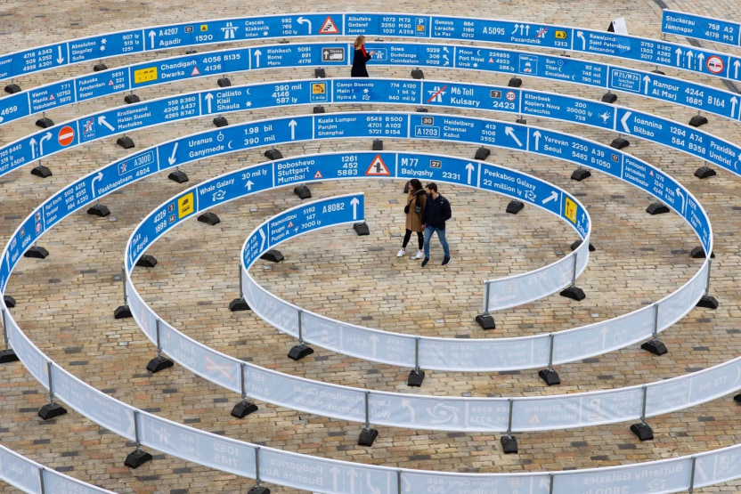 People walking in a blue spiral art installation made of road signs
