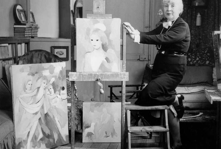 Archival black and white image of Marie Laurencin in her studio with 3 paintings in the background