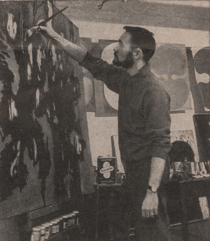 man standing in front of large artwork in his studio in 1958