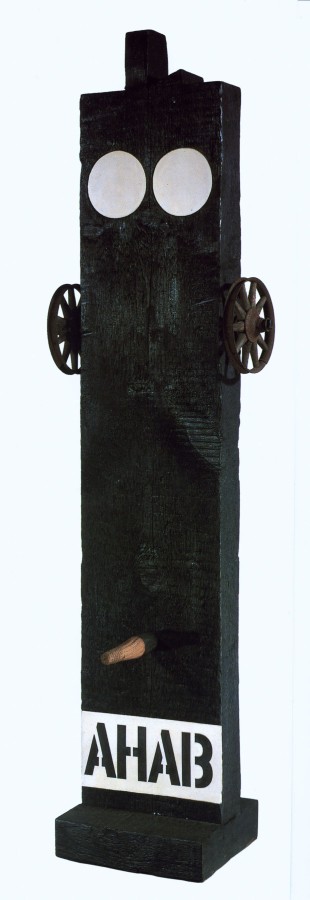 A sculpture consisting of a painted black wooden beam with a haunched tenon on a black wooden base. Across the bottom the work's title, Ahab, is painted in black stenciled letters against a white band of paint. Above the title is a wooden peg. A small wheel has been attached to both the right and left side of the upper third of the sculpture. At the top of the sculpture are two white circles.
