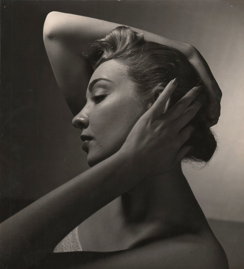 Louise Dahl-Wolfe, Untitled (N.W. Ayer), ​c. 1940. A model in profile, looking left, with hands on her head. One elbow is raised above her head, the other falls below.