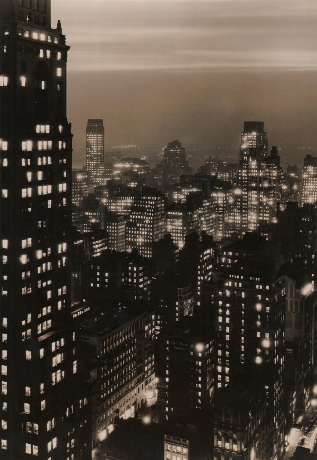 Paul J. Woolf, New York Skyline at Dusk, c. 1935. Night time cityscape with overcast sky and one building filling the left quarter of the vertical frame.