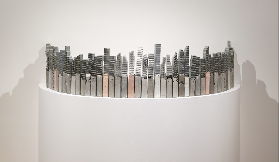 Sculpture made from cement and staple pins that looks like a city scape of tall buildings