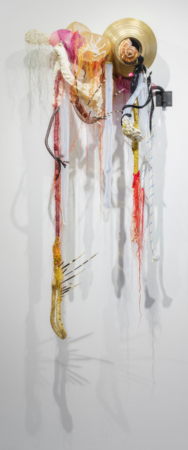 Rina Banerjee, Watering holes could not speak, like elongated wicks, drew from near to far milk and meat, holding food like holding feet from walking free., 2020,&nbsp;Moonstone beads, Czech glass beads, quartz , lava rock, cotton netting, sequin applique, sea conch, snail shells hand blown glass, Indian brass water head vessel, mohair,&nbsp;55 x 21 x 23 in (139.7 x 53.3 x 58.4 cm), &nbsp;