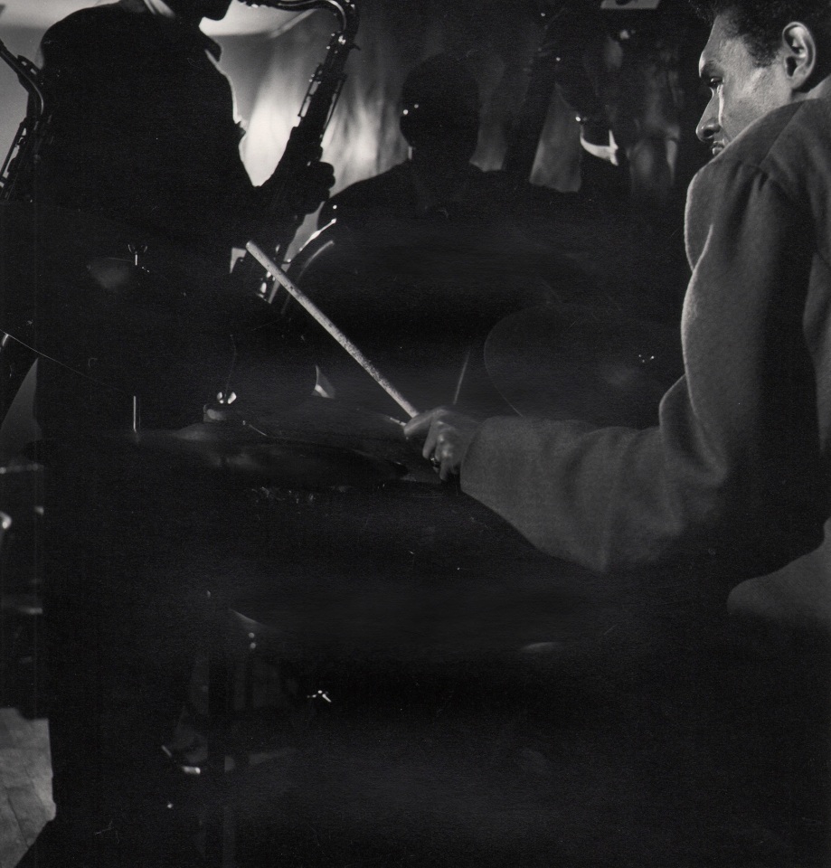 Wayne Miller, Untitled, Chicago, ​1946&ndash;1947. A band plays in a dark room. Photographed from behind the drummer.